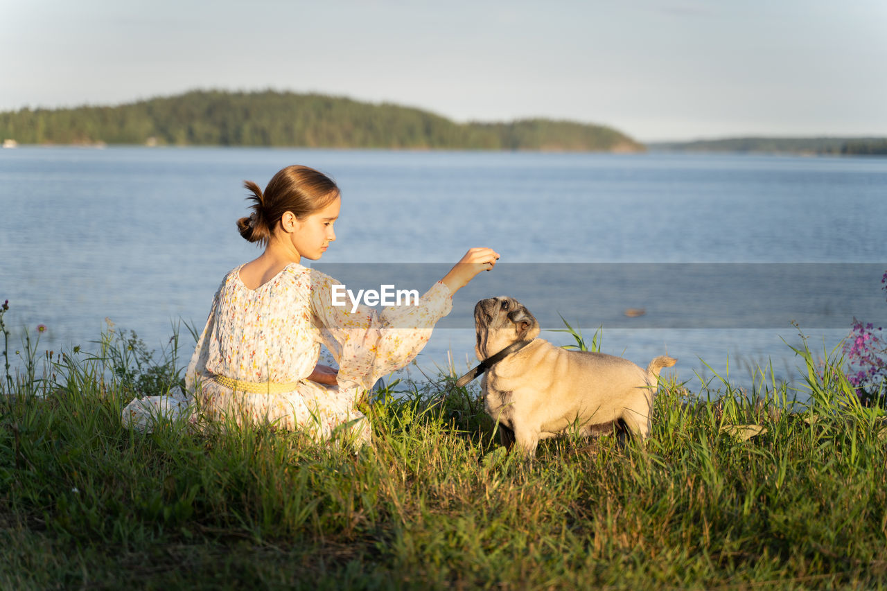 A girl and a pug on the lake shore