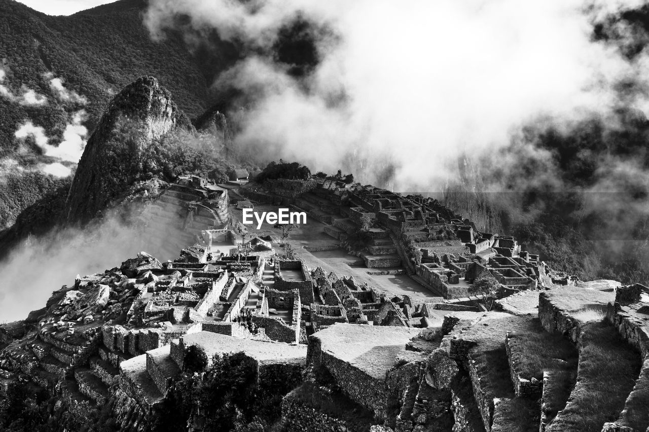 Ruined structures on landscape against clouds