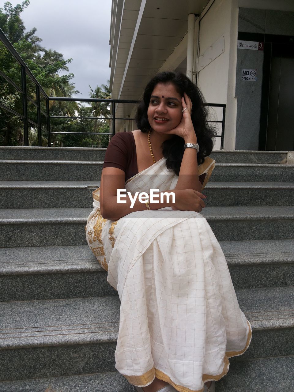 Smiling woman wearing sari while sitting on staircase