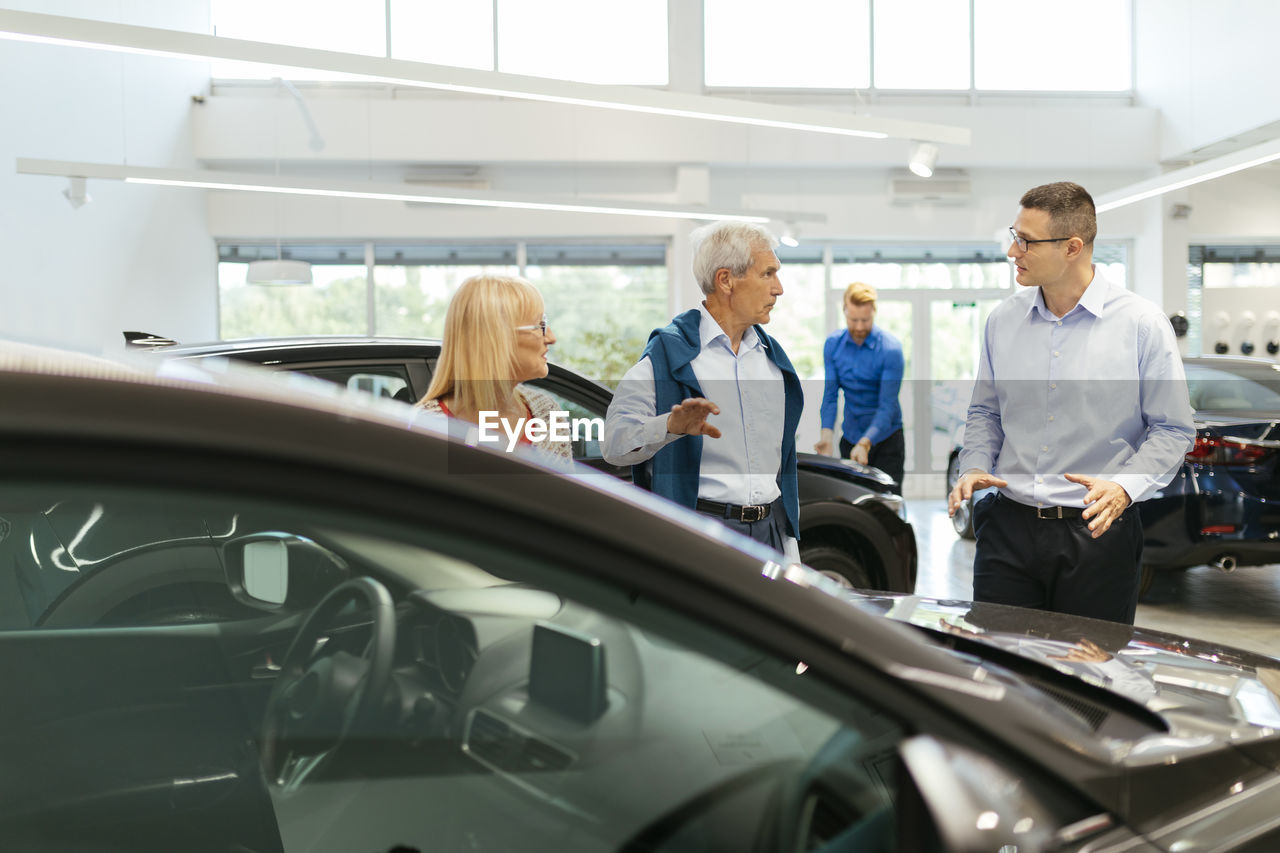 Salesman advising customers in car dealership