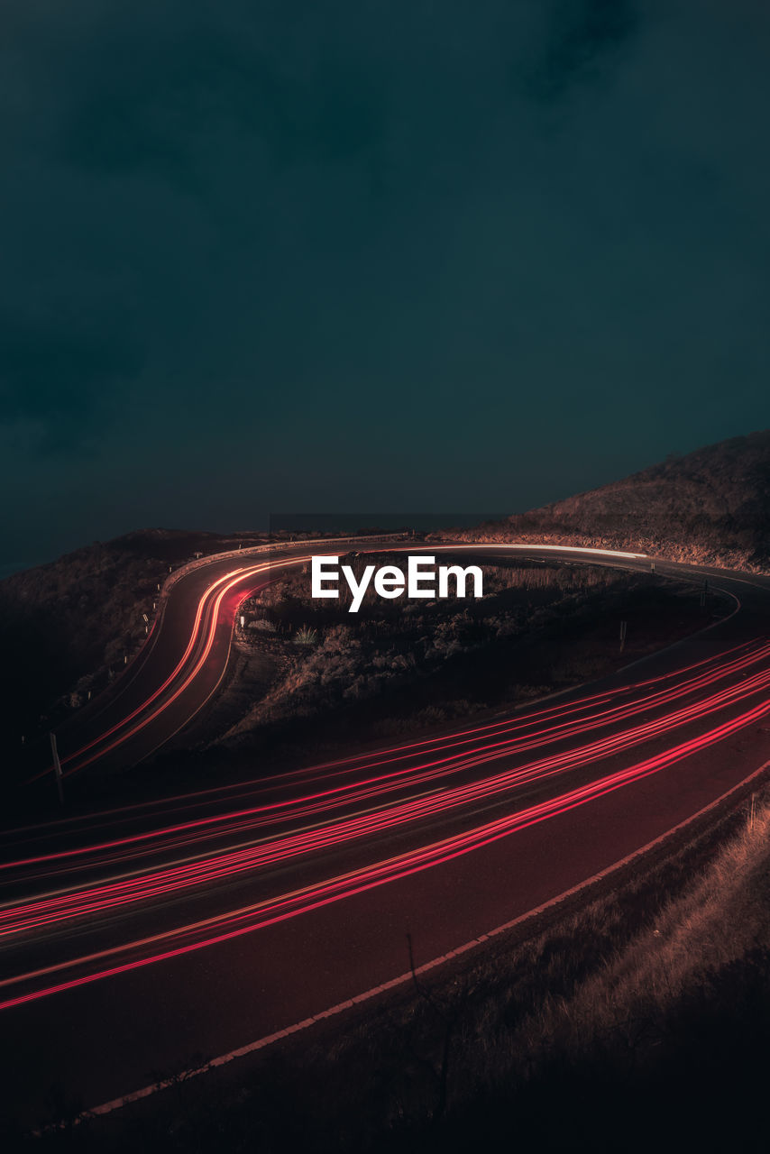 Light trails on road against sky at night