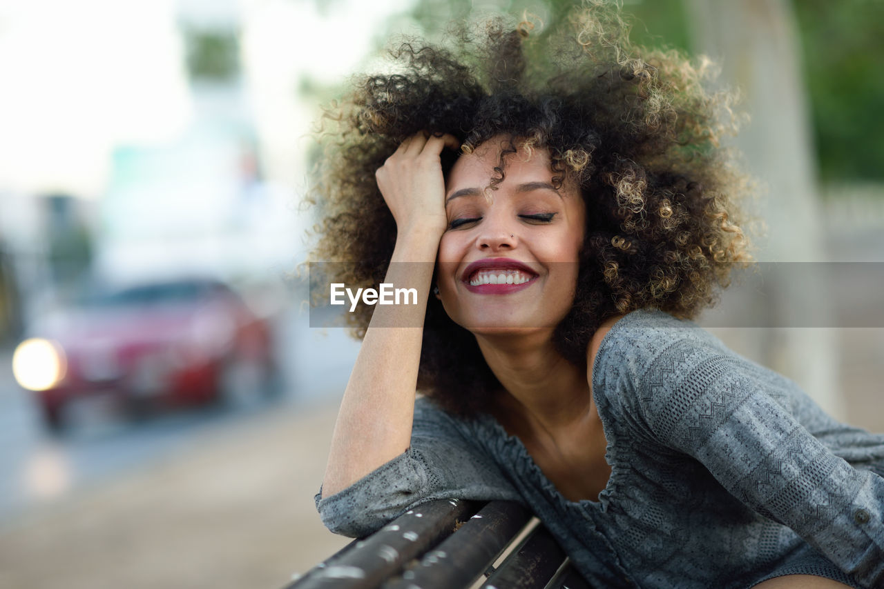 Smiling young woman with curly hair in city