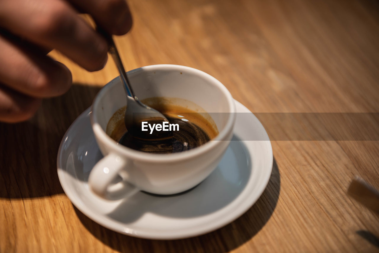 CLOSE-UP OF COFFEE CUP AND SPOON ON TABLE