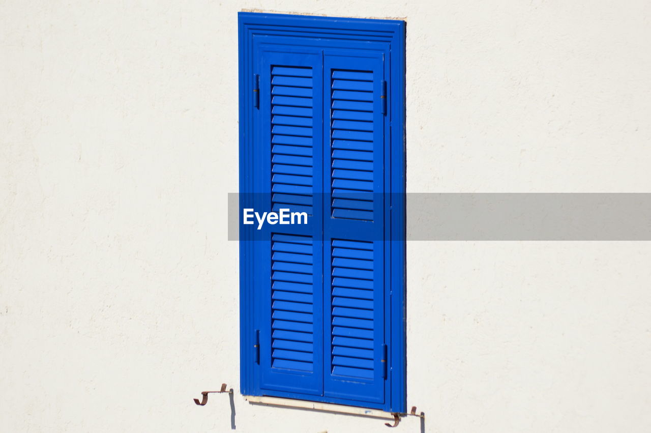 Close-up of blue window on white wall