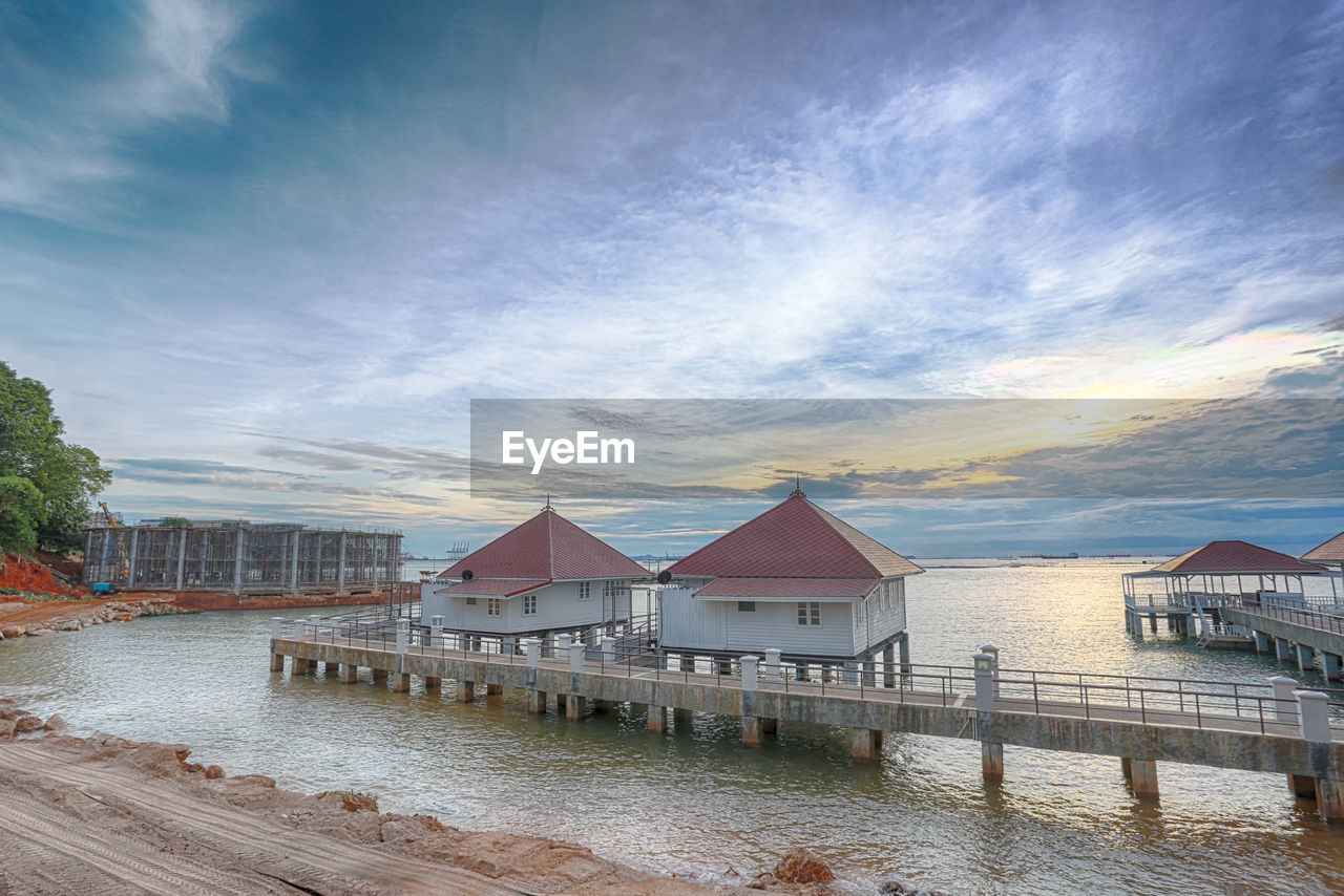 HOUSES BY SEA AGAINST SKY AT SUNSET