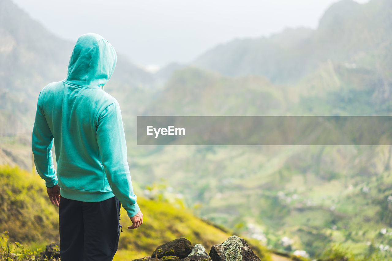 Tourist in hoodie in front of rural landscape in paul valley. santo antao island, cape verde
