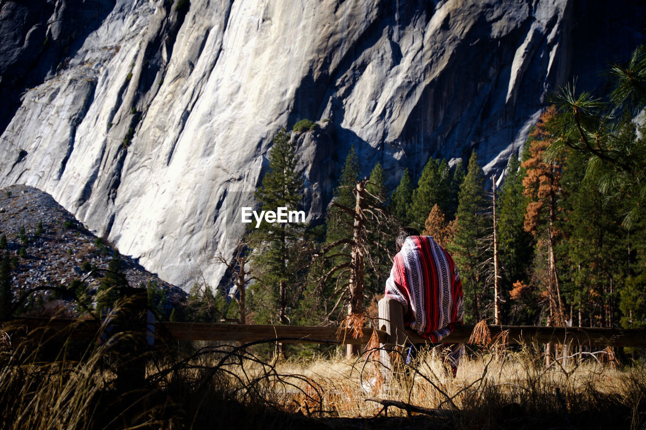 Rear view of man walking on rock by mountain