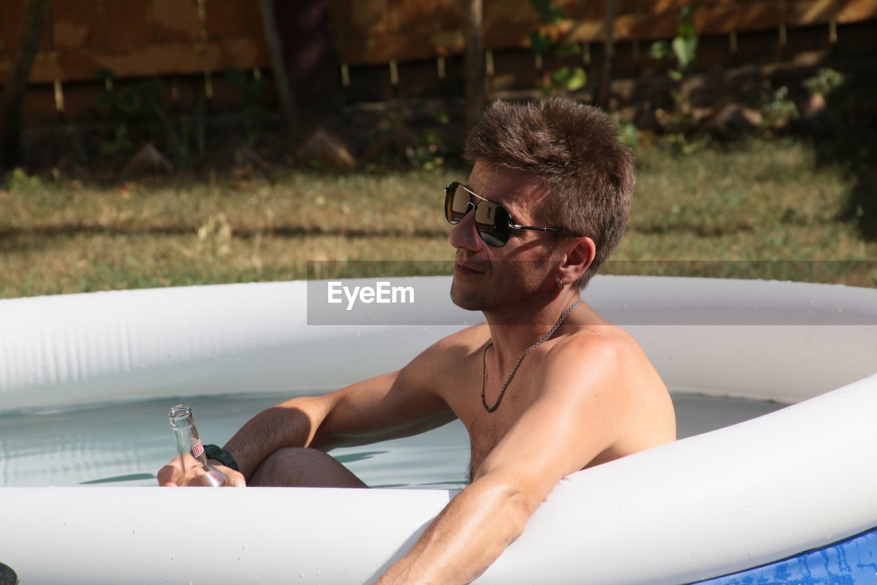Man having drink while relaxing in wadding pool