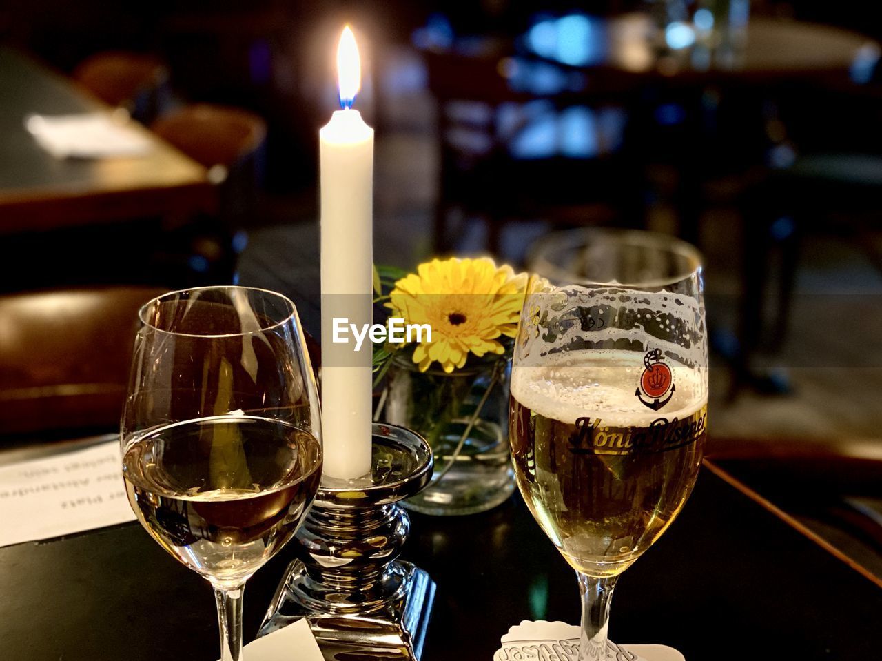 Tea light candles on glass table with beer and wine