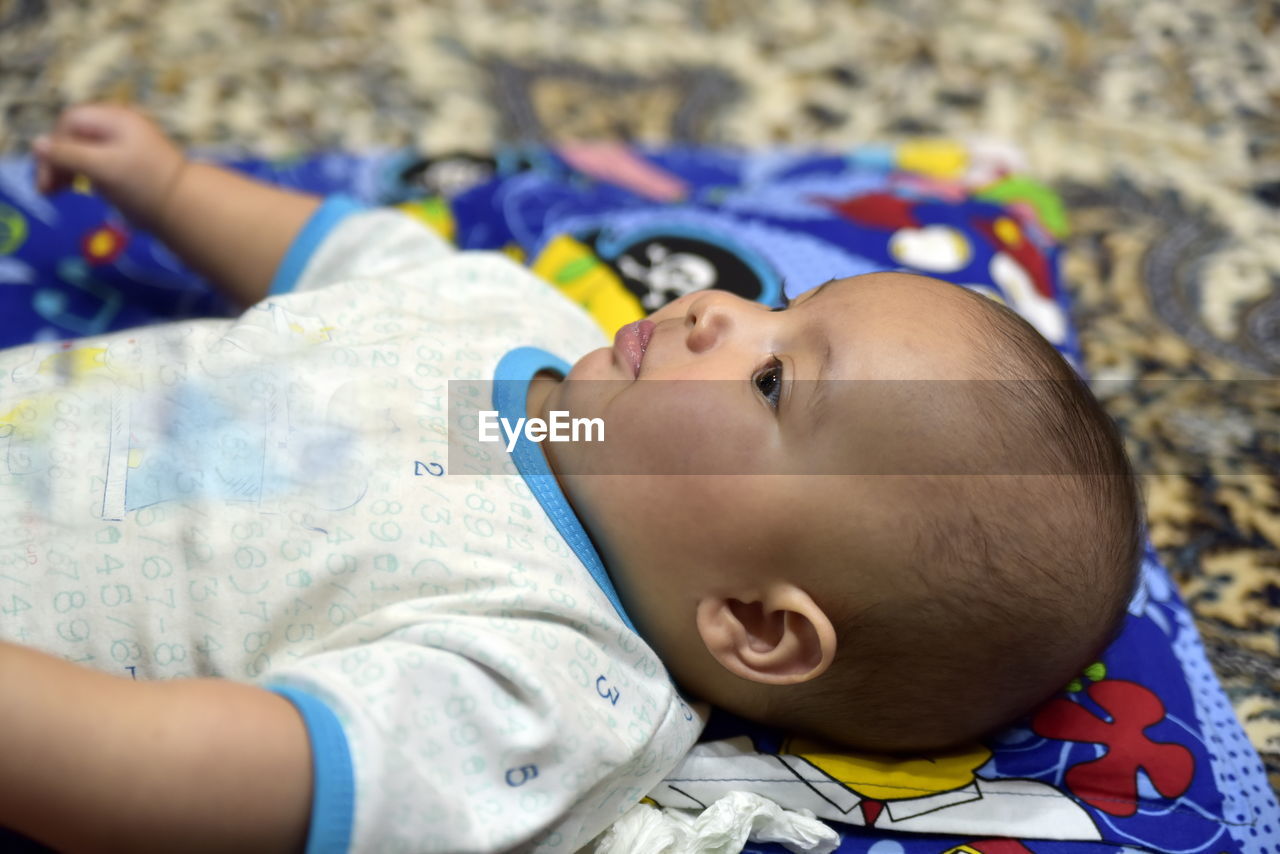 HIGH ANGLE VIEW OF BABY RELAXING ON BED