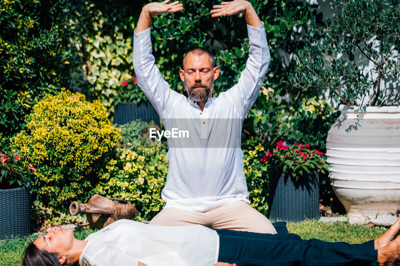 Reiki energy healing. woman lying with her eyes closed, reiki practitioner above her body.