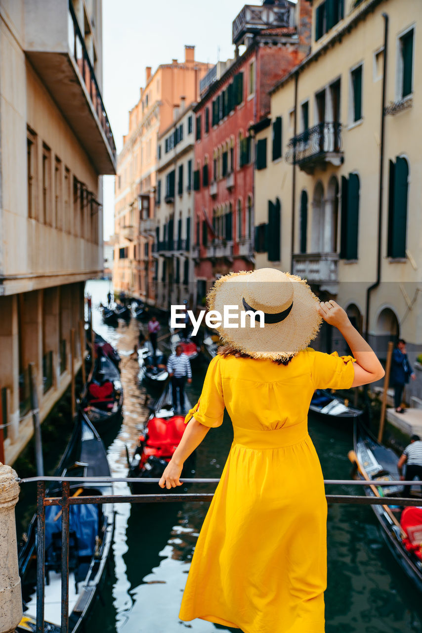 rear view of woman wearing hat while standing in city