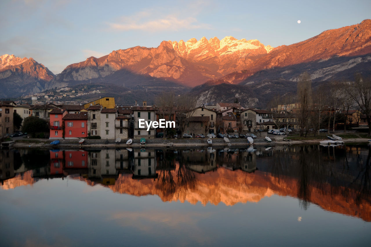 Reflection of buildings in lake against sky during sunset