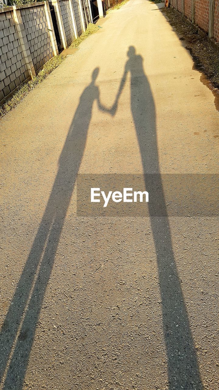 SHADOW OF MAN AND WOMAN ON ZEBRA CROSSING