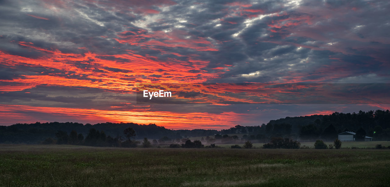 Scenic view of dramatic sky over land during sunset