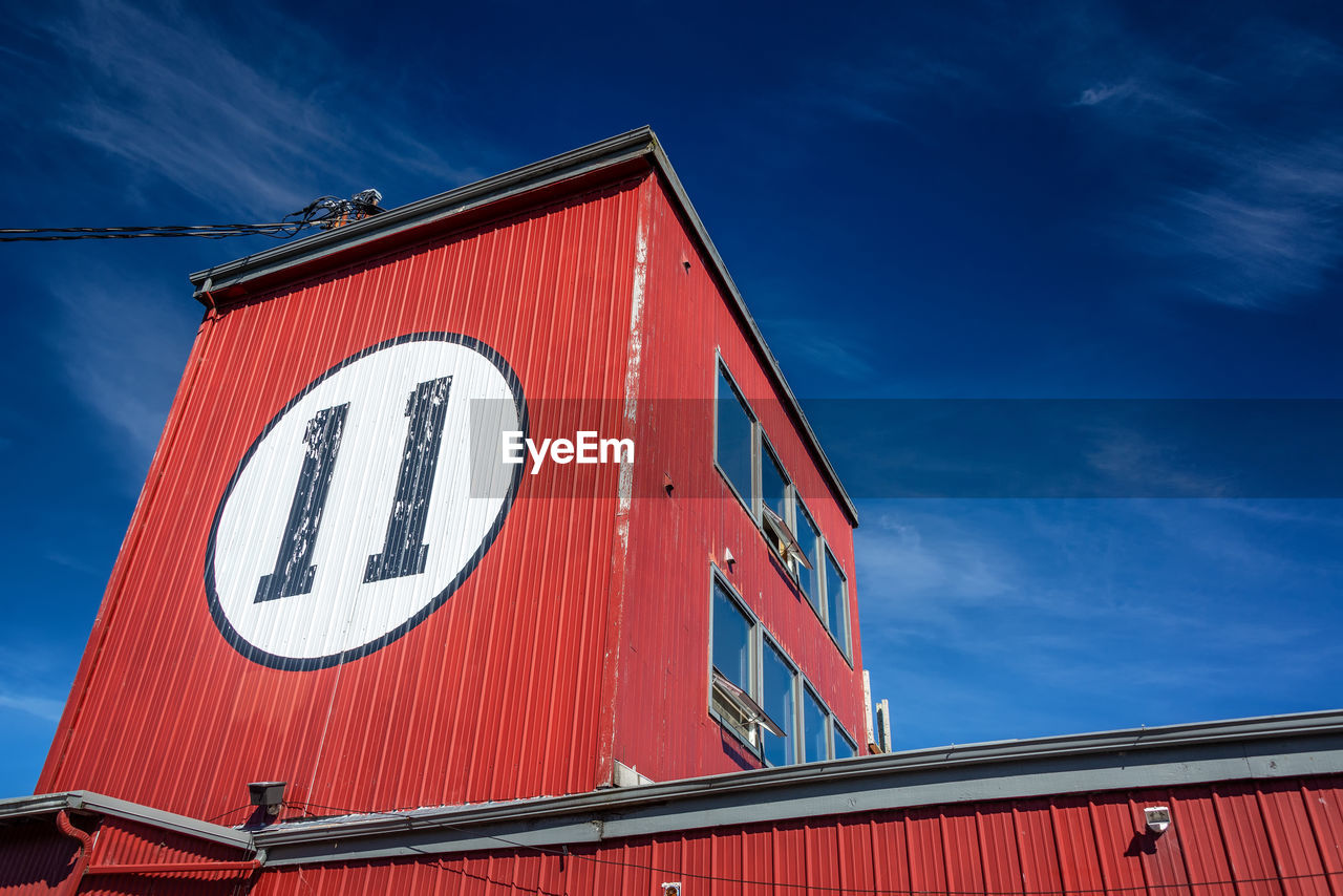 LOW ANGLE VIEW OF RED INFORMATION SIGN AGAINST BUILDING