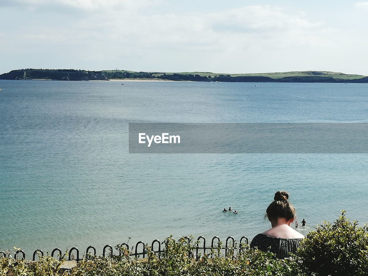 REAR VIEW OF WOMAN STANDING ON SEA AGAINST SKY