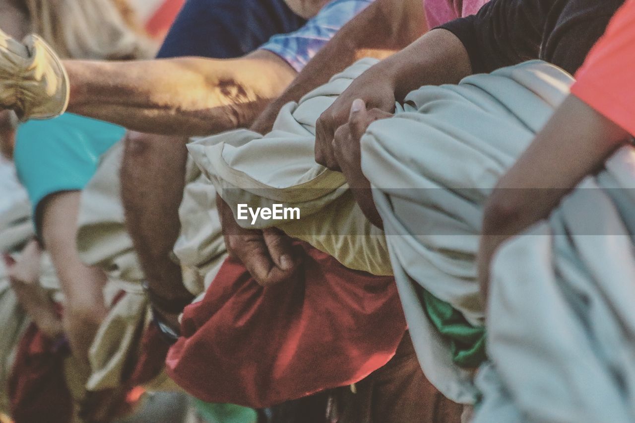 Midsection of people holding fabric