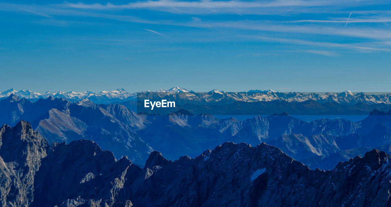 Scenic view of snowcapped mountains against blue sky