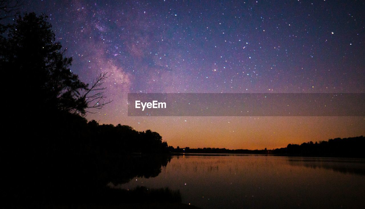 Calm lake below starry sky