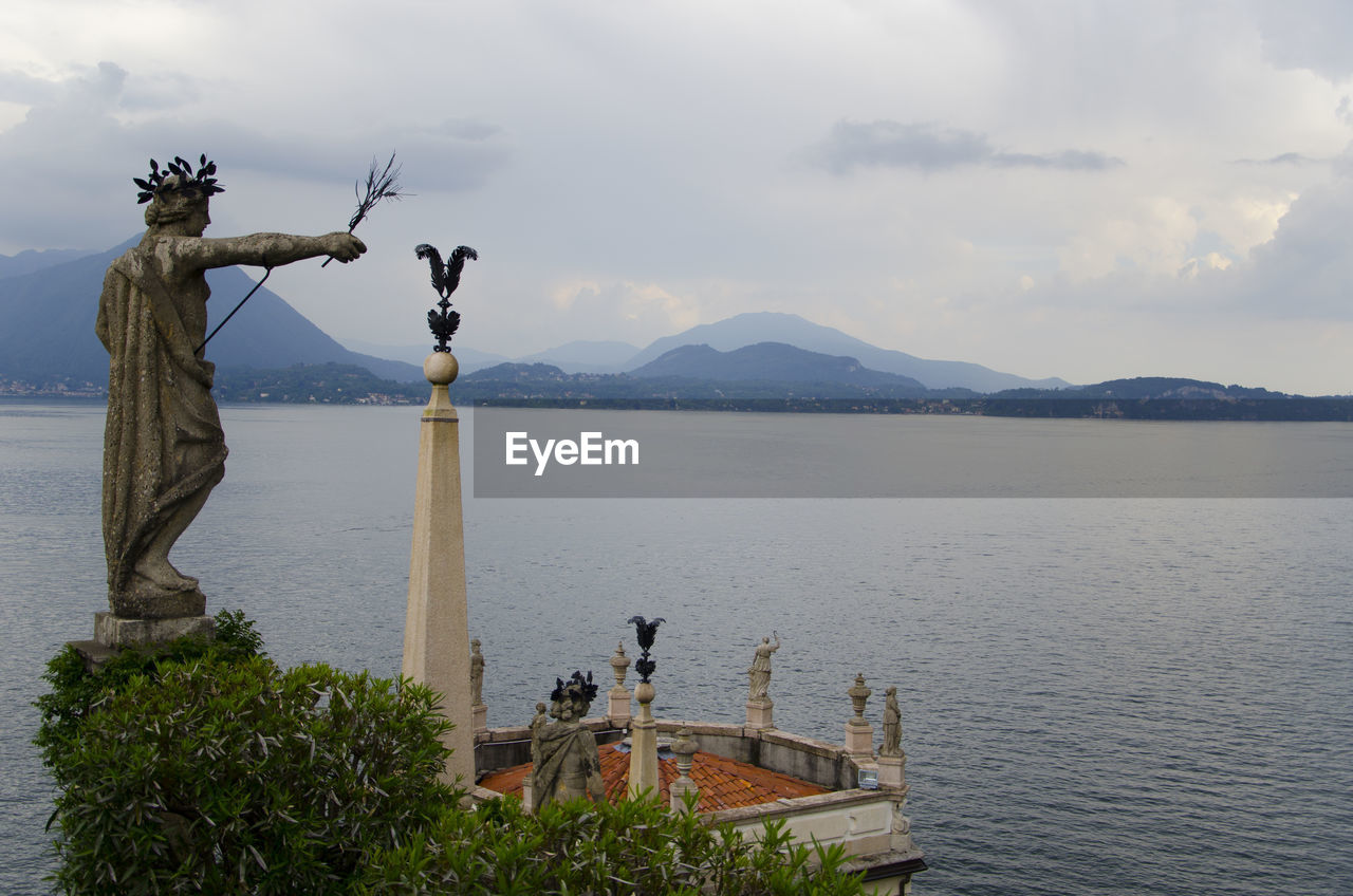 Statue by sea against sky