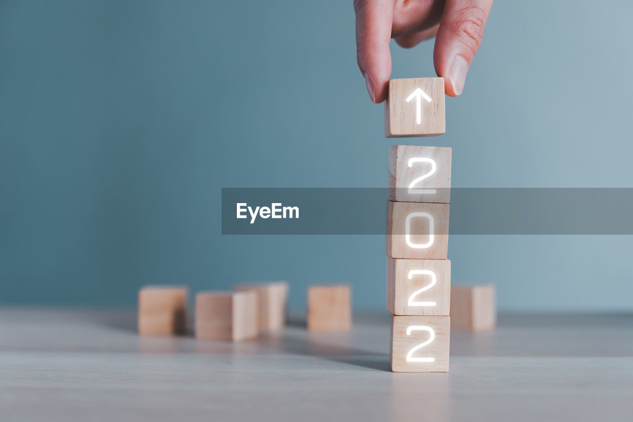 cropped hand of man with toy blocks with text on wooden block on table