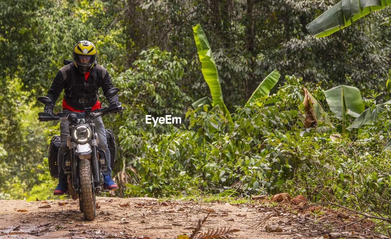 Man riding his scrambler type motorcycle through forrest