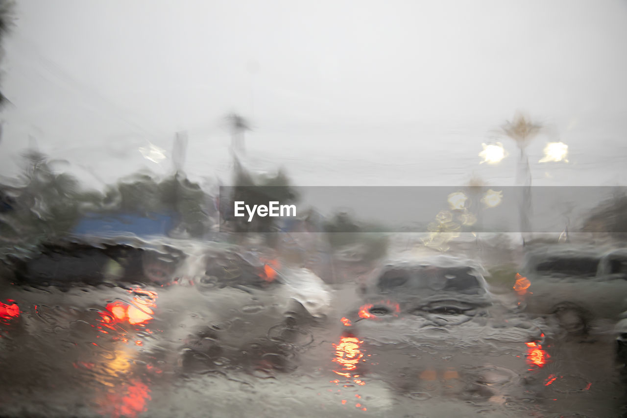 Traffic on road seen through windshield during rainy season