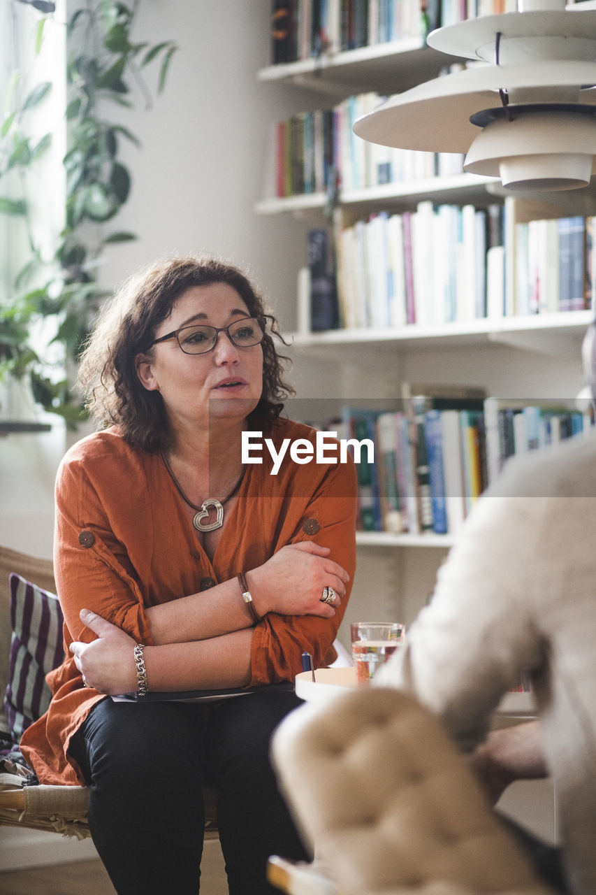 Mature female therapist talking to patient at home office