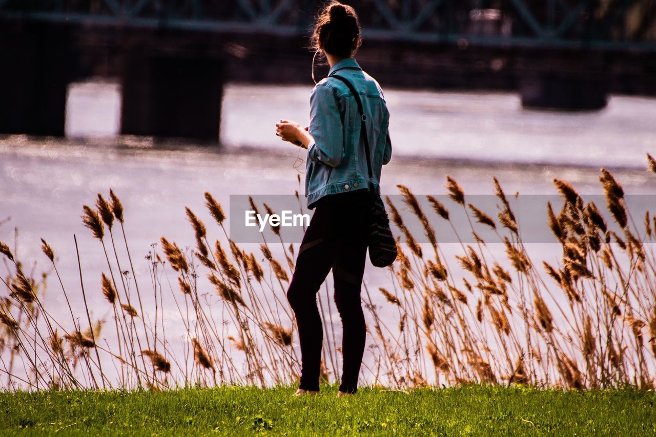 Women standing on field by lake