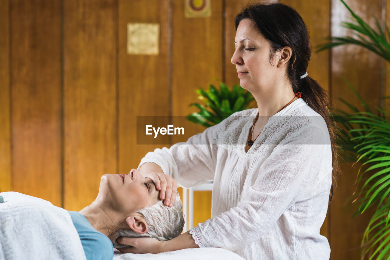 Smiling woman giving massage to client at spa