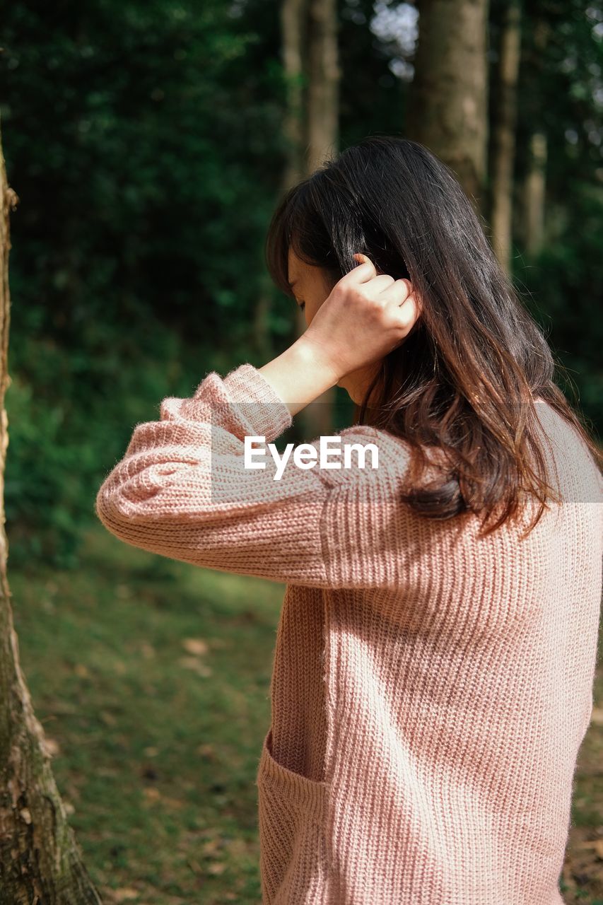 MIDSECTION OF WOMAN STANDING ON TREE