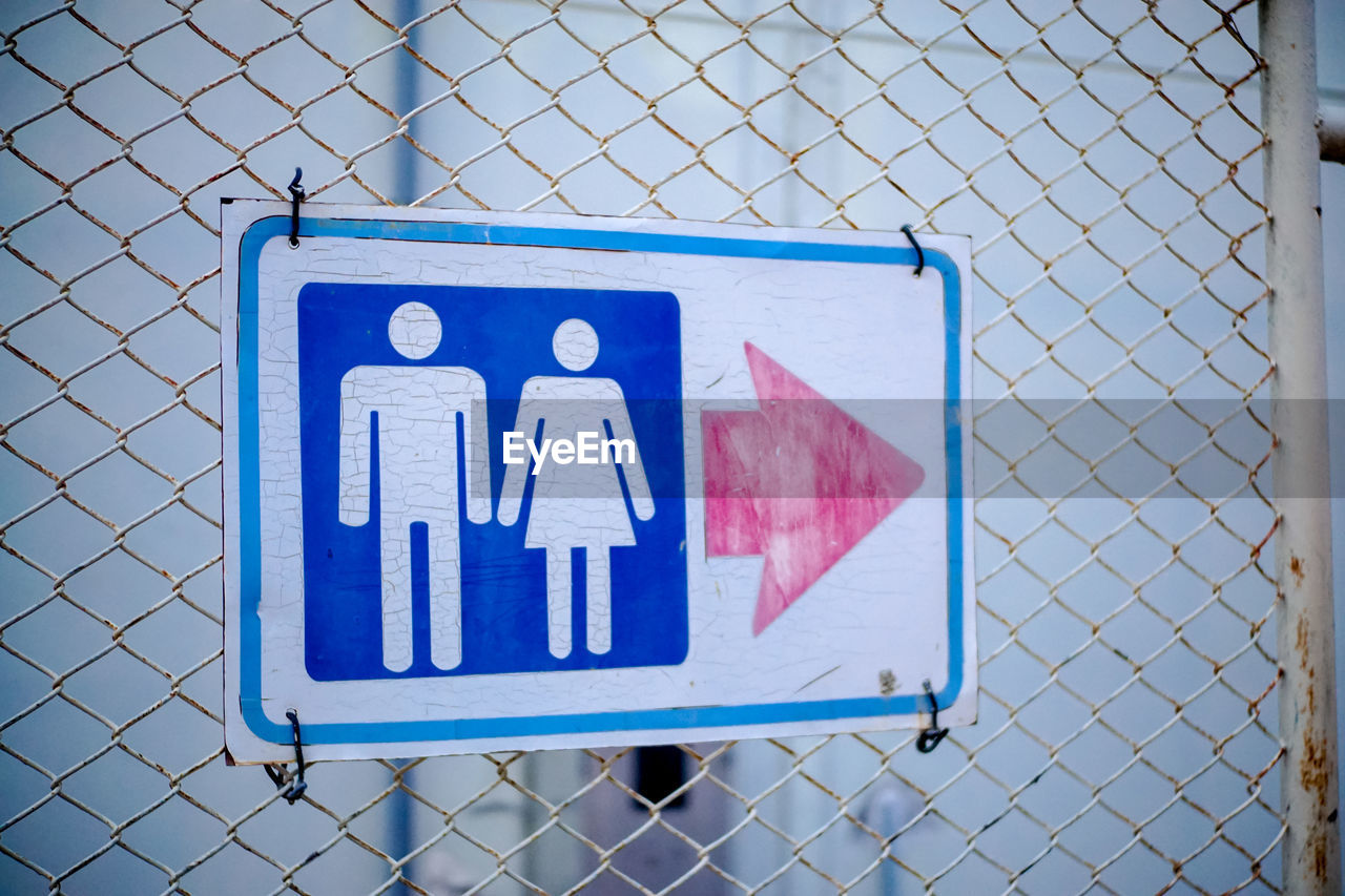 Close-up of toilet sign on fence