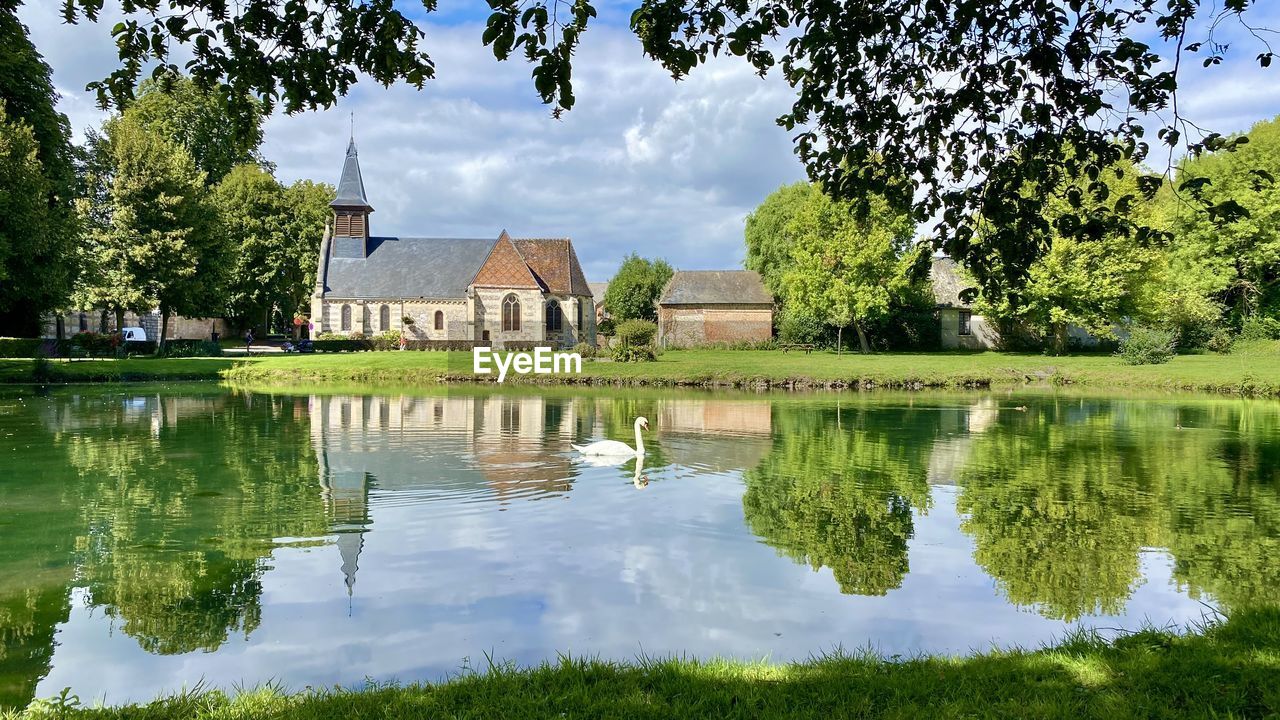 water, reflection, plant, tree, architecture, lake, built structure, nature, building, building exterior, sky, house, garden, beauty in nature, tranquility, residential district, no people, cloud, green, château, estate, mansion, grass, day, landscape, travel destinations, outdoors, scenics - nature, park, tranquil scene, history, autumn, environment, rural area, flower, home, the past, religion, waterway