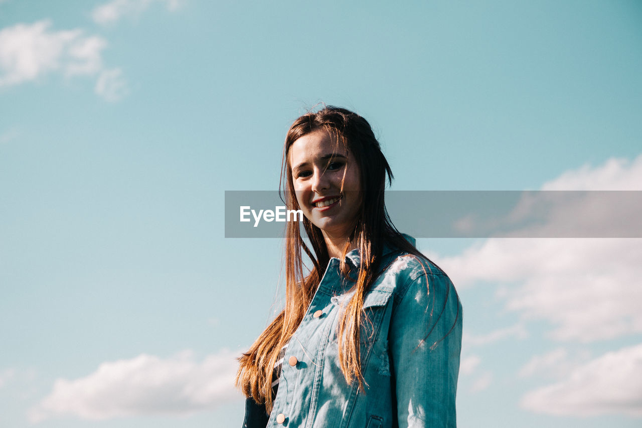 Portrait of smiling woman standing against sky