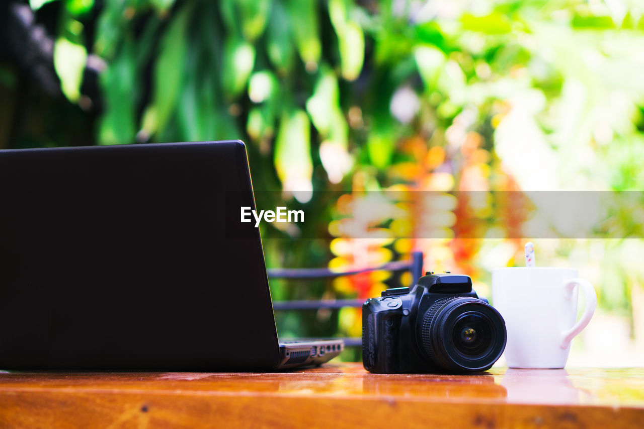 CLOSE-UP OF CAMERA ON TABLE AGAINST BLURRED BACKGROUND