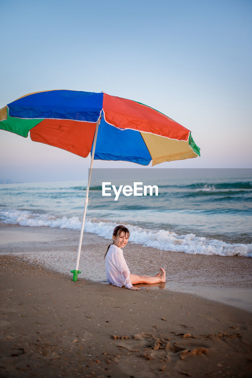 rear view of woman with umbrella on beach