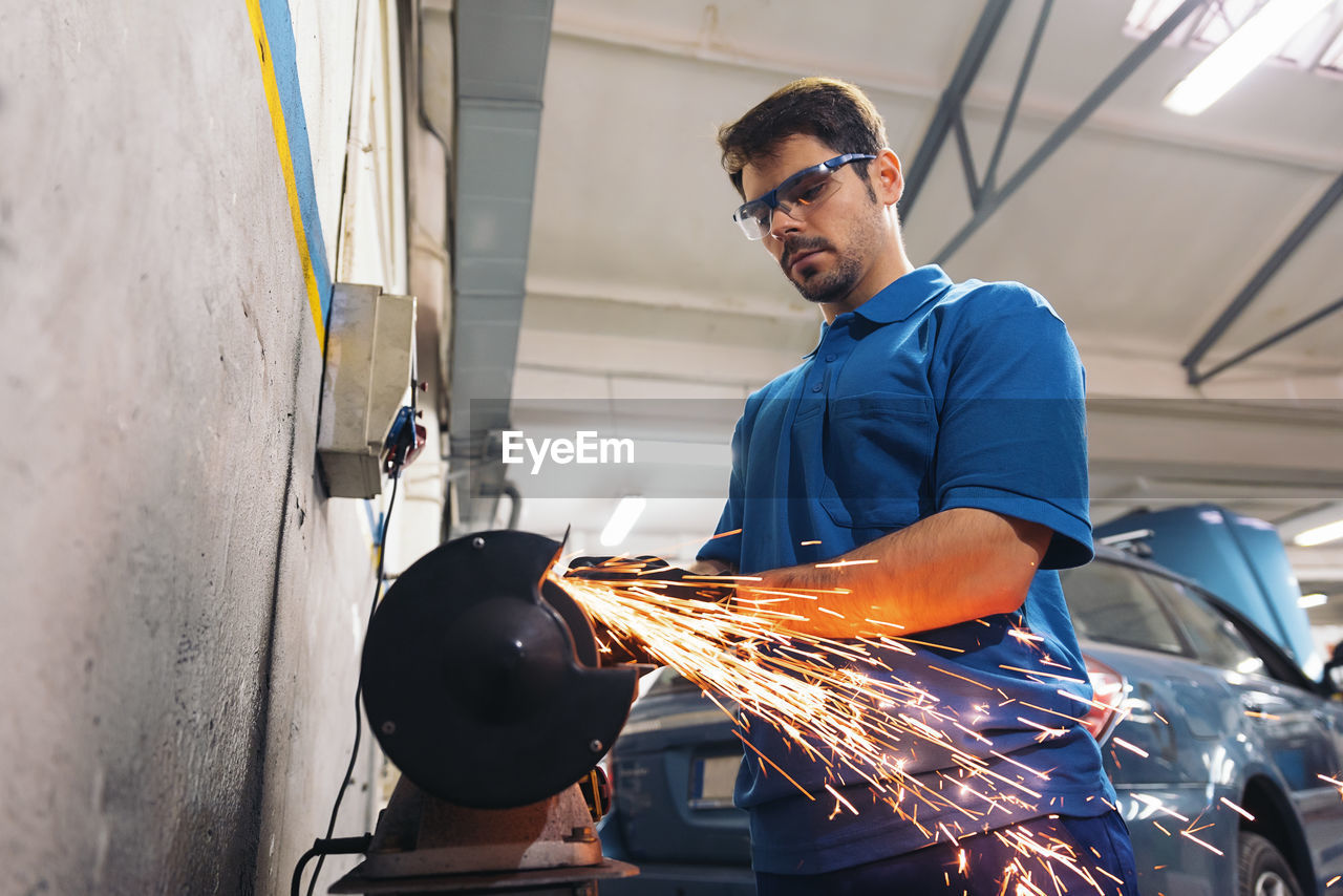 Low angle view of mechanic welding in garage