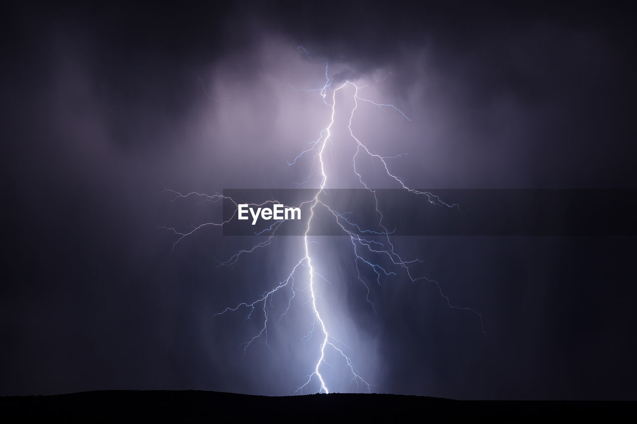 A lightning bolt illuminates rain falling from a thunderstorm near kearny, arizona.