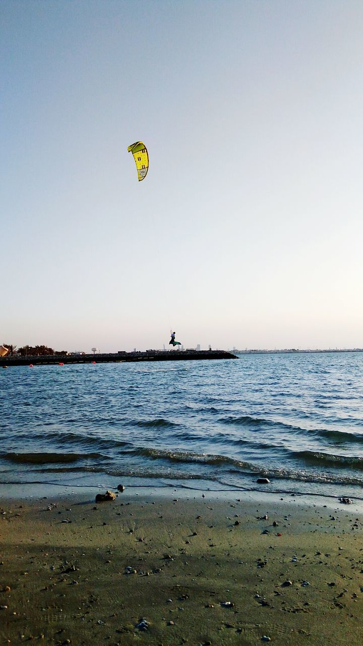 PERSON PARAGLIDING IN SEA AGAINST CLEAR SKY