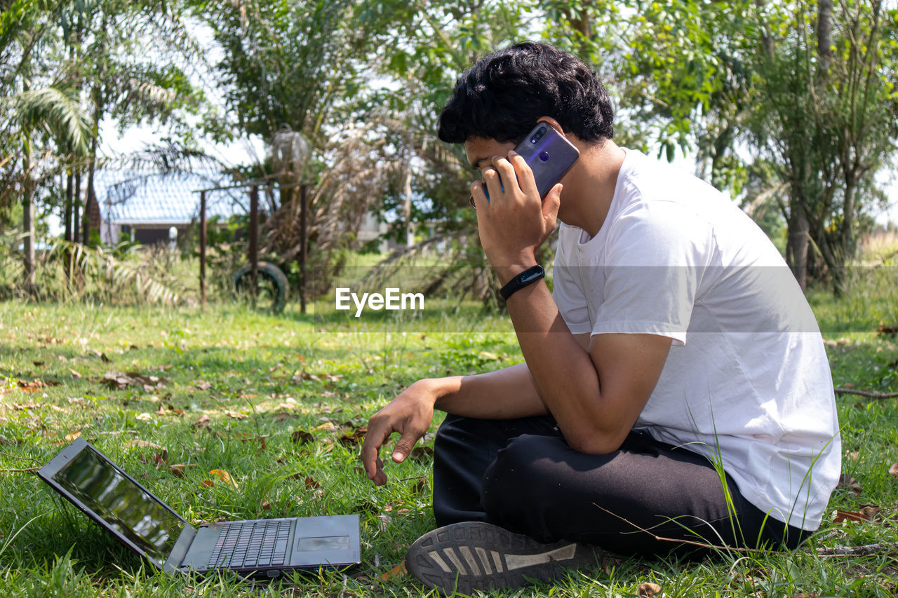 Man photographing while sitting on field