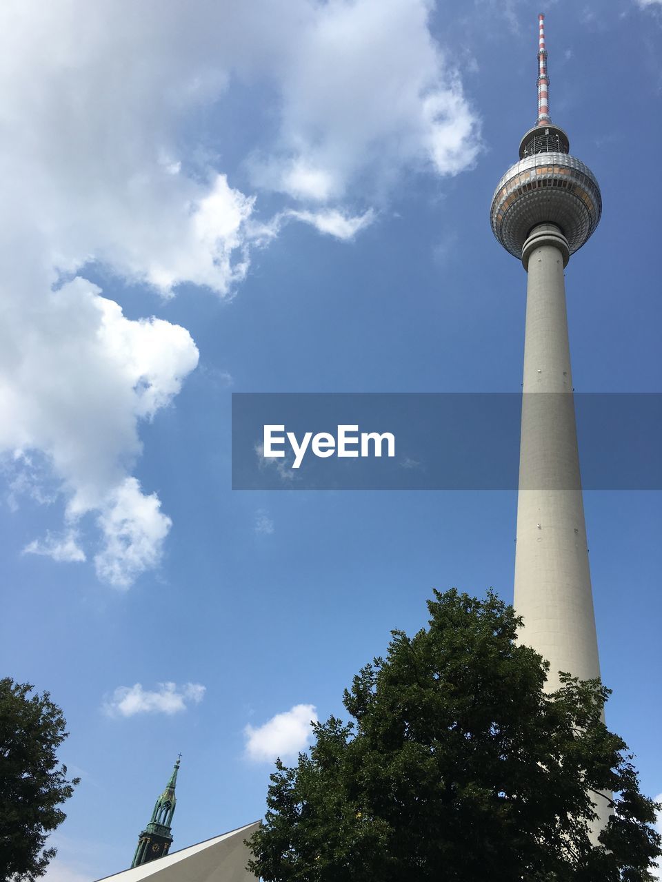 Low angle view of communications tower against cloudy sky