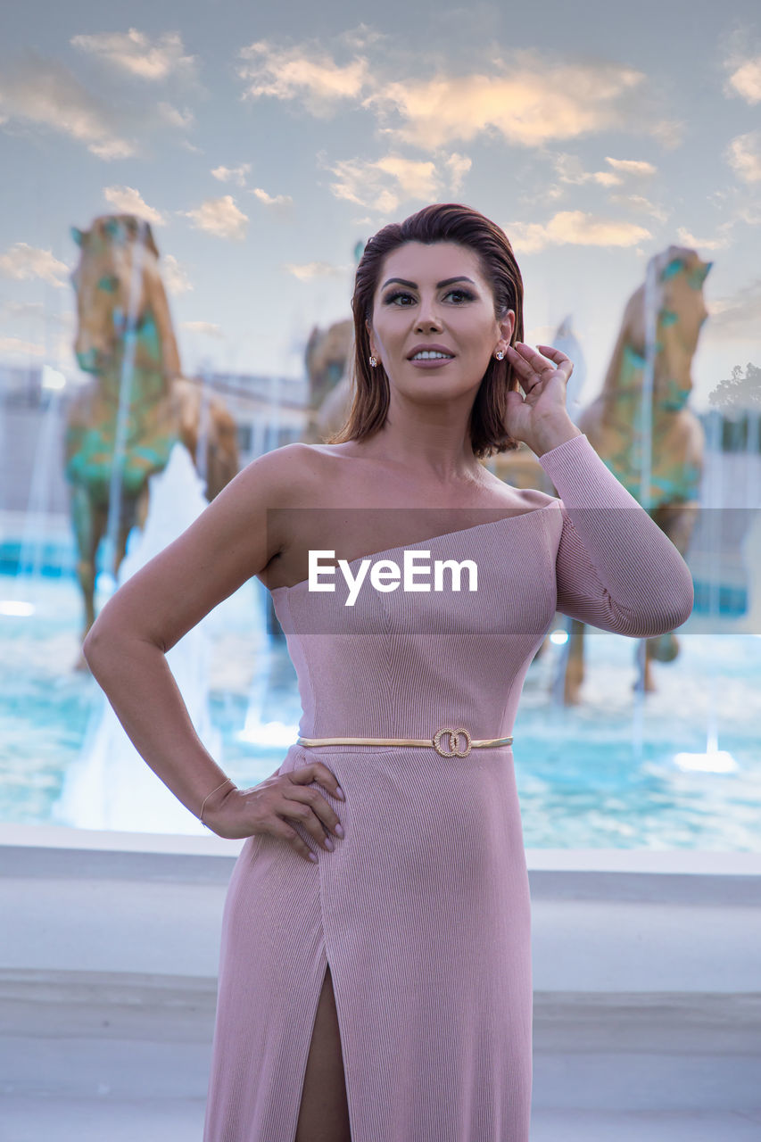 PORTRAIT OF A YOUNG WOMAN STANDING IN SWIMMING POOL