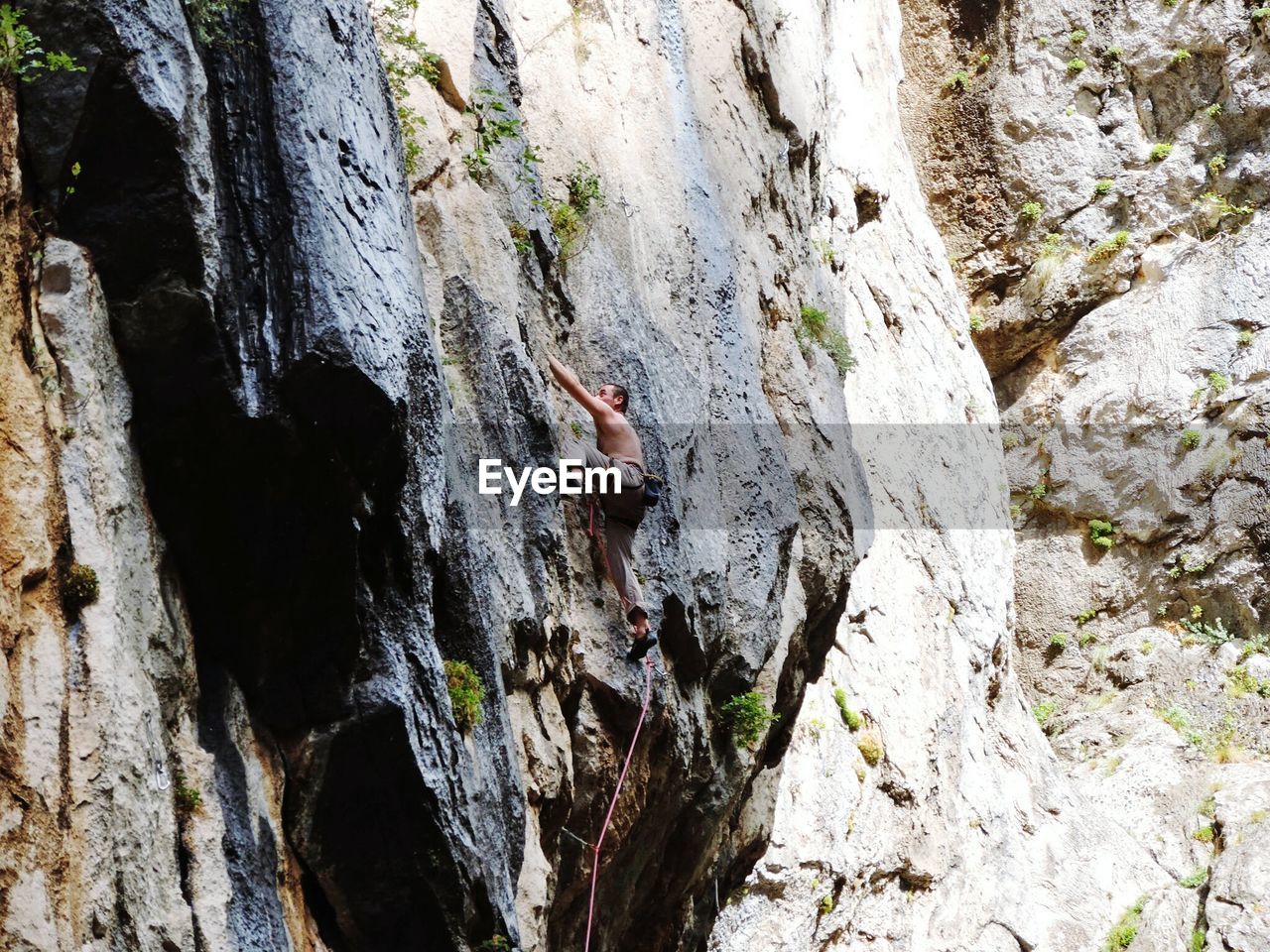 Low angle view of man climbing on rocky mountain