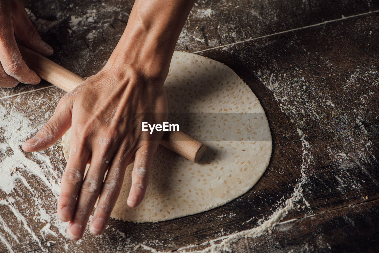 Cropped hands preparing flatbread on table