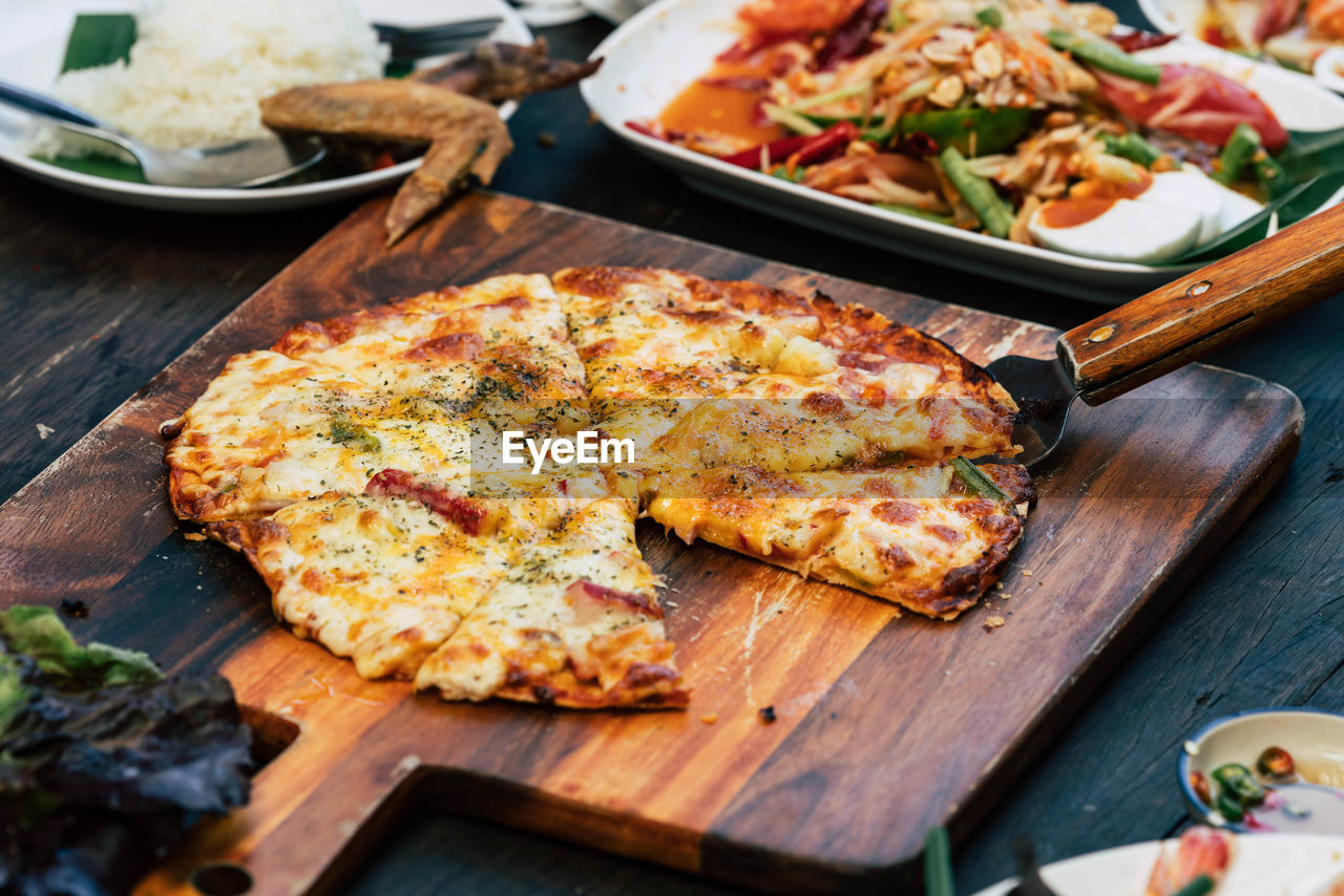 Homemade pizza with spicy asian food on wood table