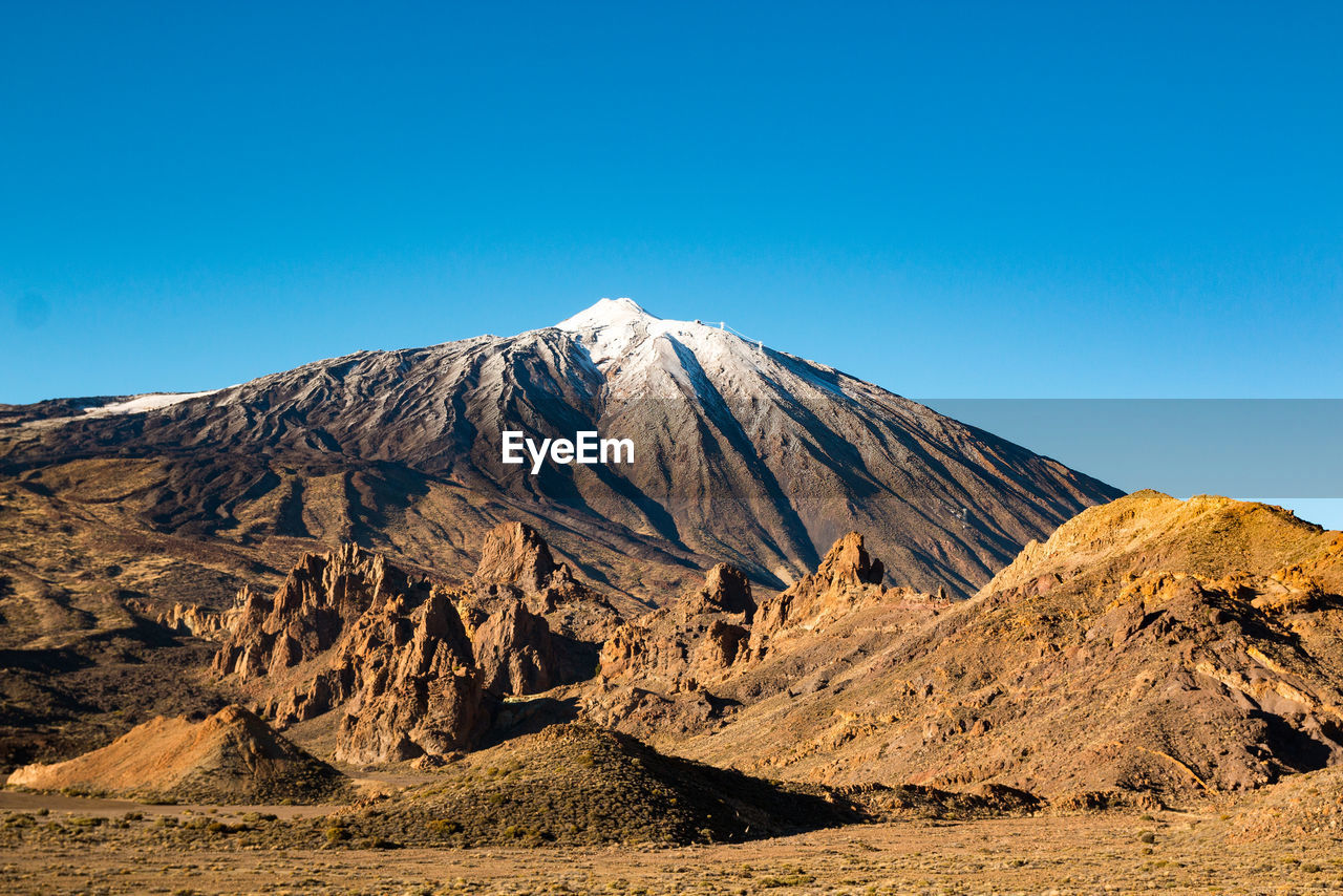 Scenic view of volcanic mountain against clear blue sky