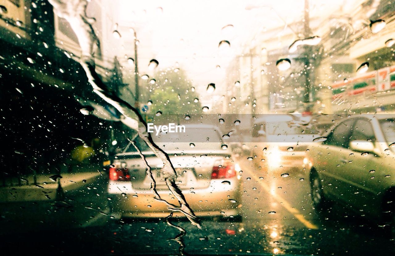 Cars on city street seen through wet windshield