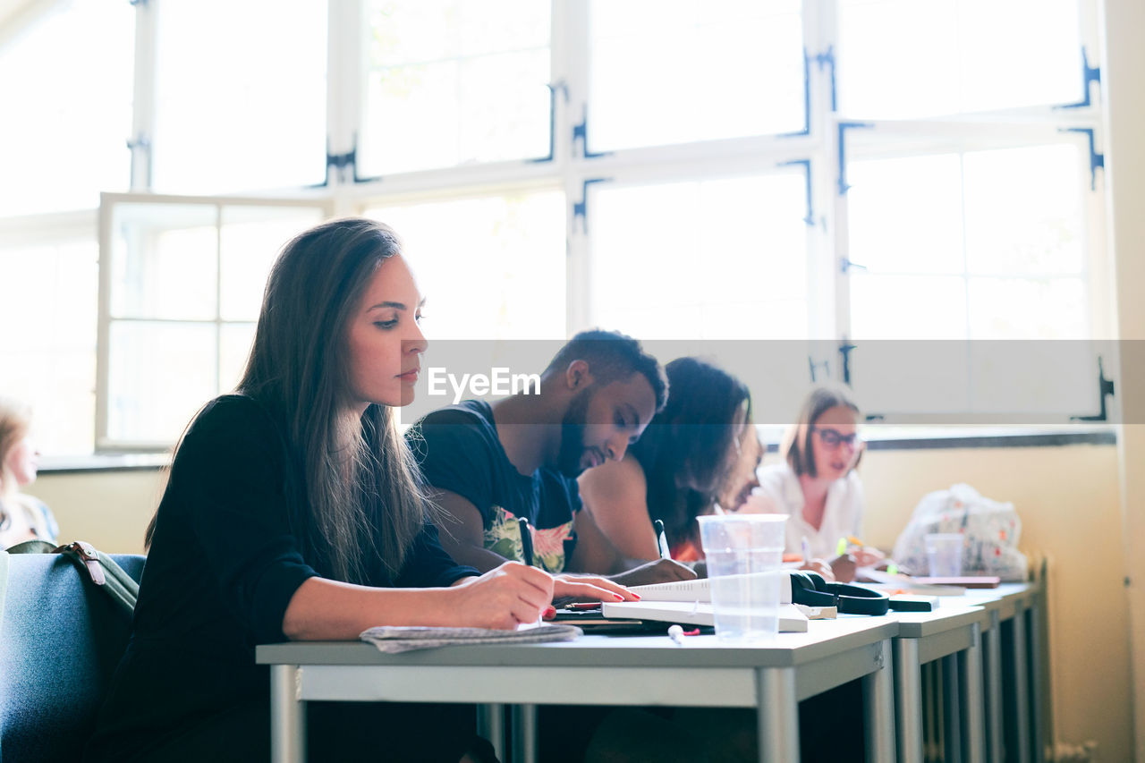 Mid adult woman studying with classmates in language school