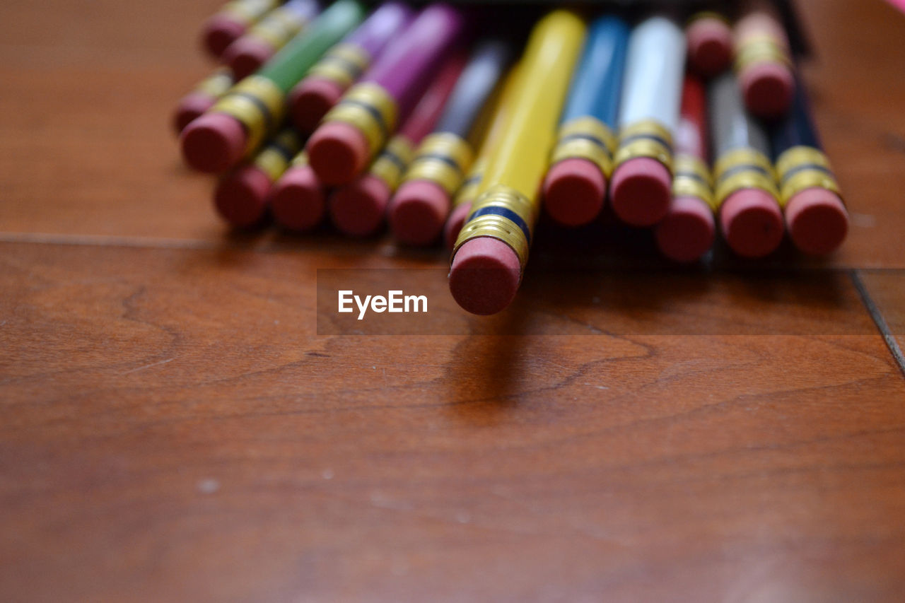 A group of pencils lying on a wooden surface,